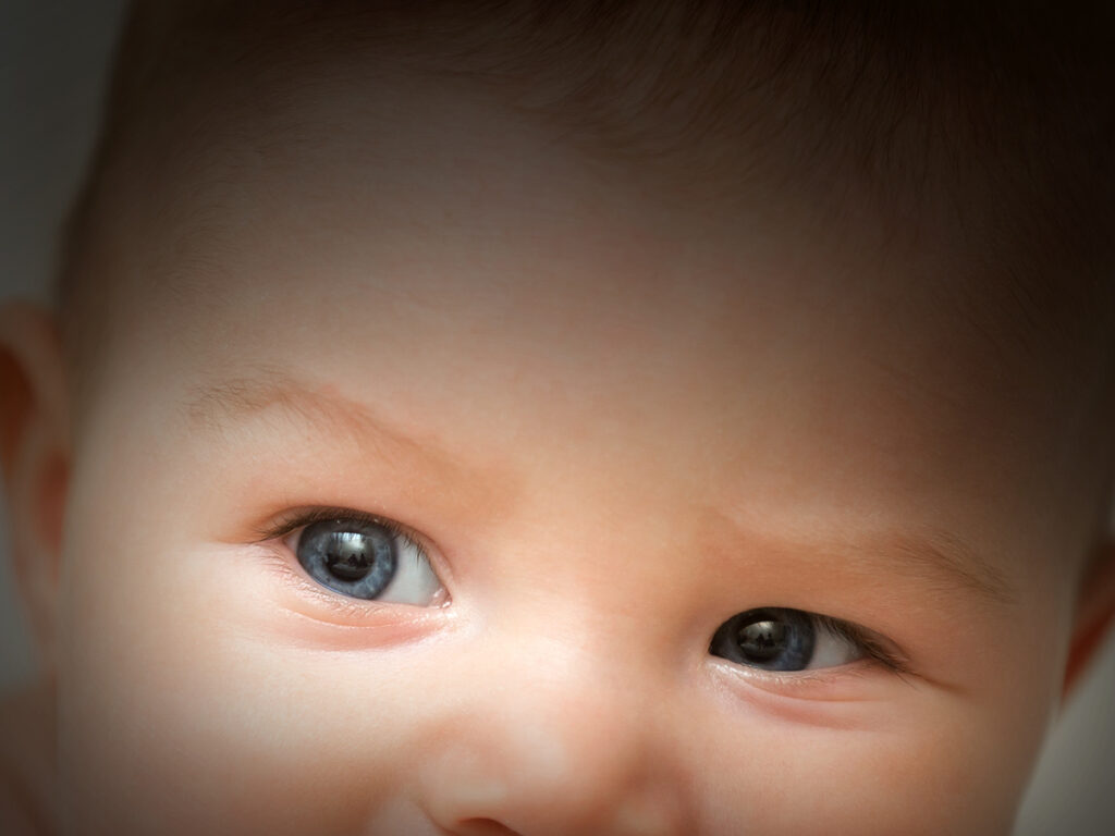 Adorable baby biting the board of his wooden cot